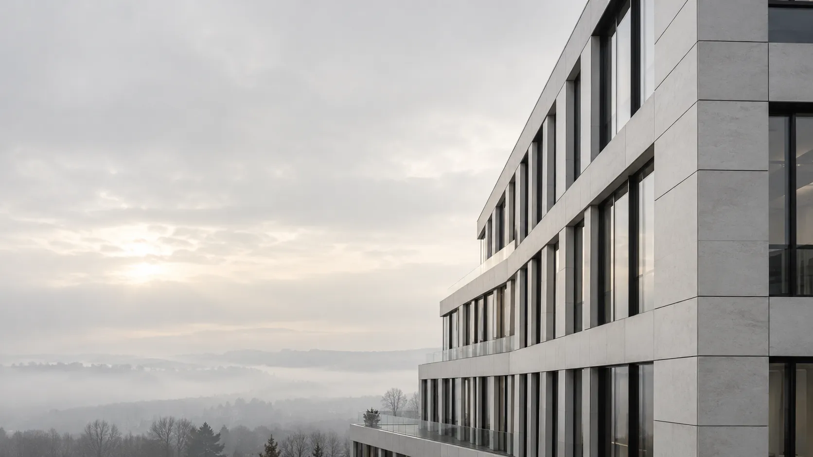 Moderne Bürofassade aus großformatigen hellen Platten im Morgendunst
